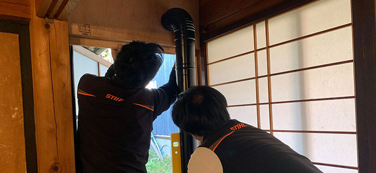 水平器をあてながら、煙突が垂直に立ち上がるかを二人で見ているところ