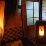 火が入った炉内を近くから見たようすと、障子の並ぶ部屋に置かれて灯りのともったペレットストーブ