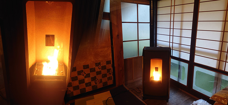火が入った炉内を近くから見たようすと、障子の並ぶ部屋に置かれて灯りのともったペレットストーブ